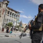 عنصر أمن سوري يؤمن خروج مدنيين من حيي الشيخ مقصود والأشرفية بحلب (AP)