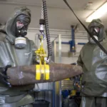 مفتشو الأسلحة يتعاملون مع ذخيرة كيميائية وهمية خلال عرض صحفي (جيتي)