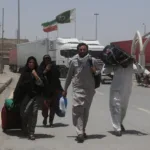 باكستانيون يسيرون حاملين أمتعتهم بعد عودتهم من إيران عقب حرب يونيو/حزيران 2025 (رويترز)